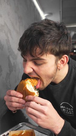 Person holding a homemade burger inside Maijard Smashburgers burger restaurant in Amsterdam.