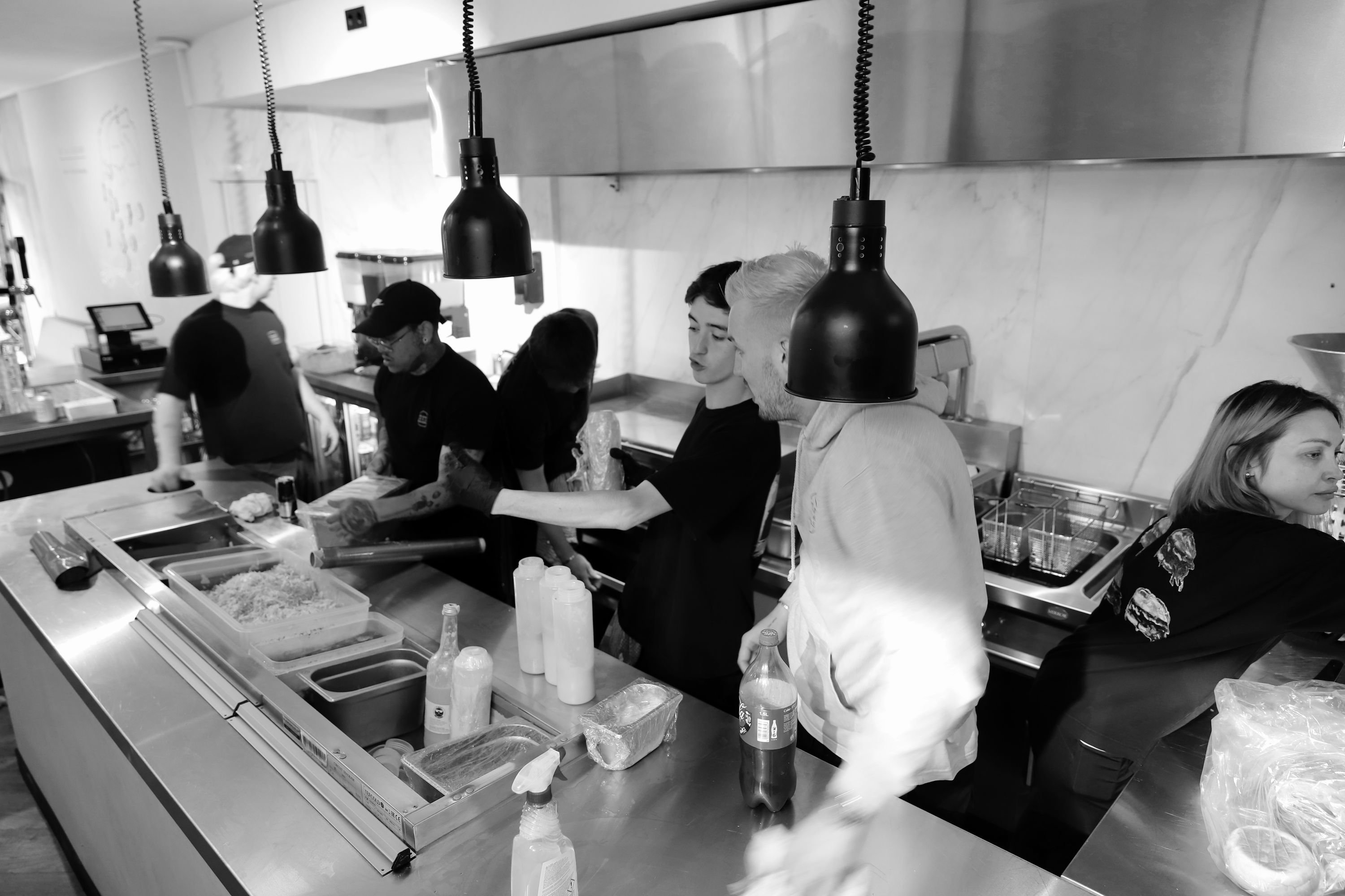Busy kitchen with multiple staff preparing food behind the counter at Maijard Smashburgers burger restaurant in Amsterdam.