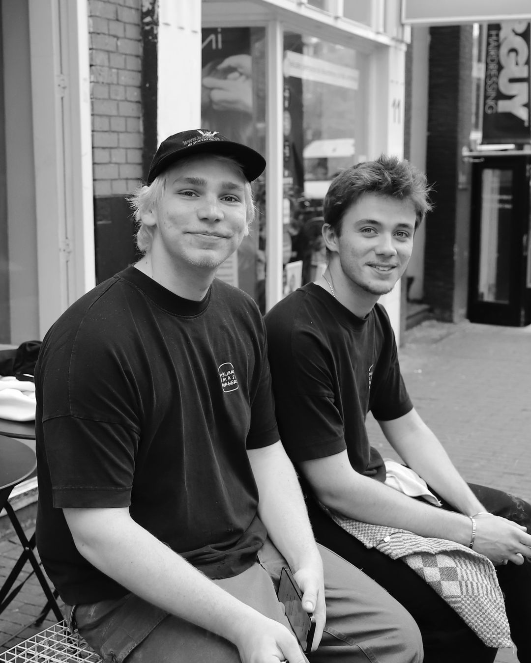 Two people dressed in Maijard Smashburgers black shirts sit outside the burger restaurant in Amsterdam.