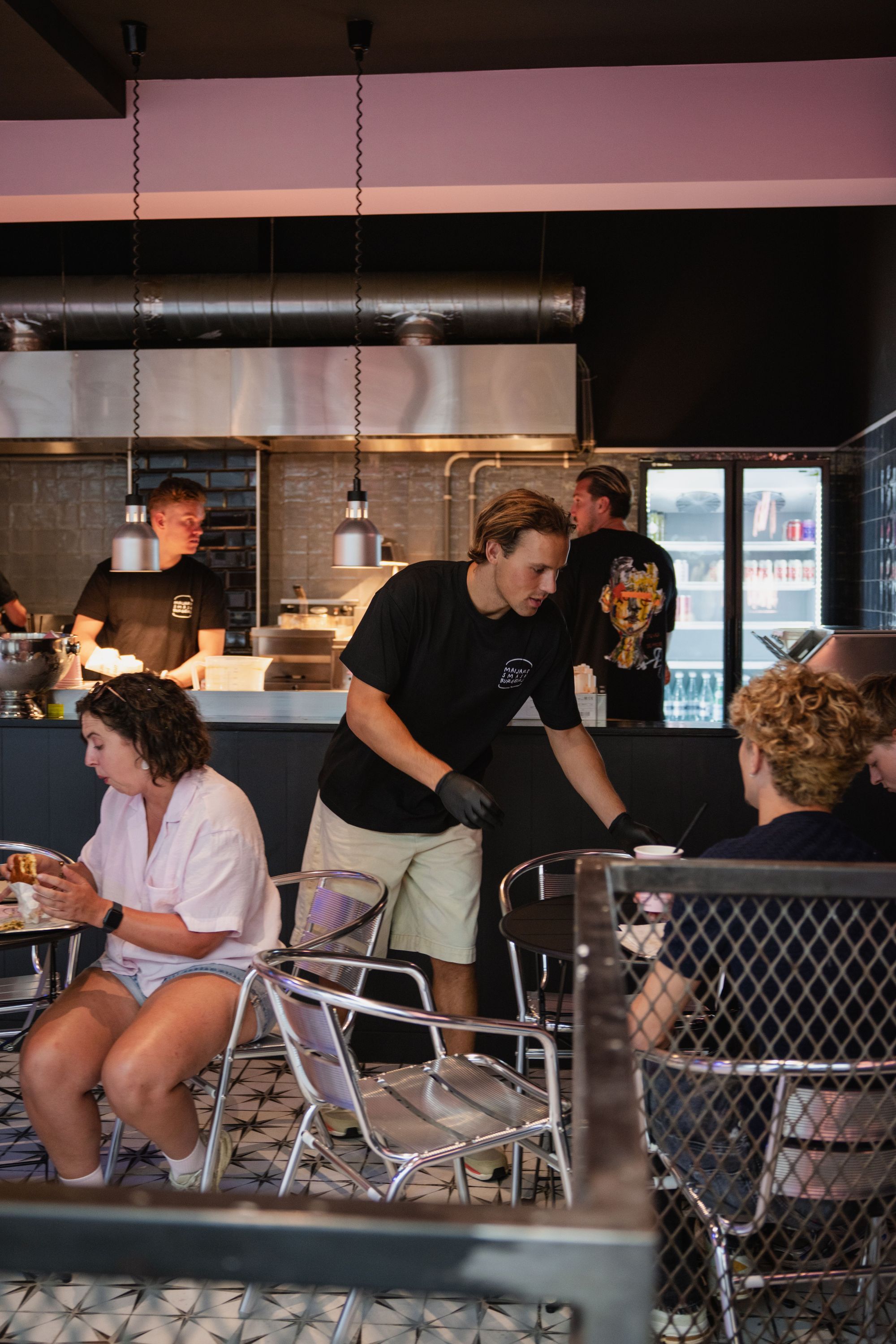 Interior of Maijard Smashburgers with staff serving customers in a modern burger restaurant setting